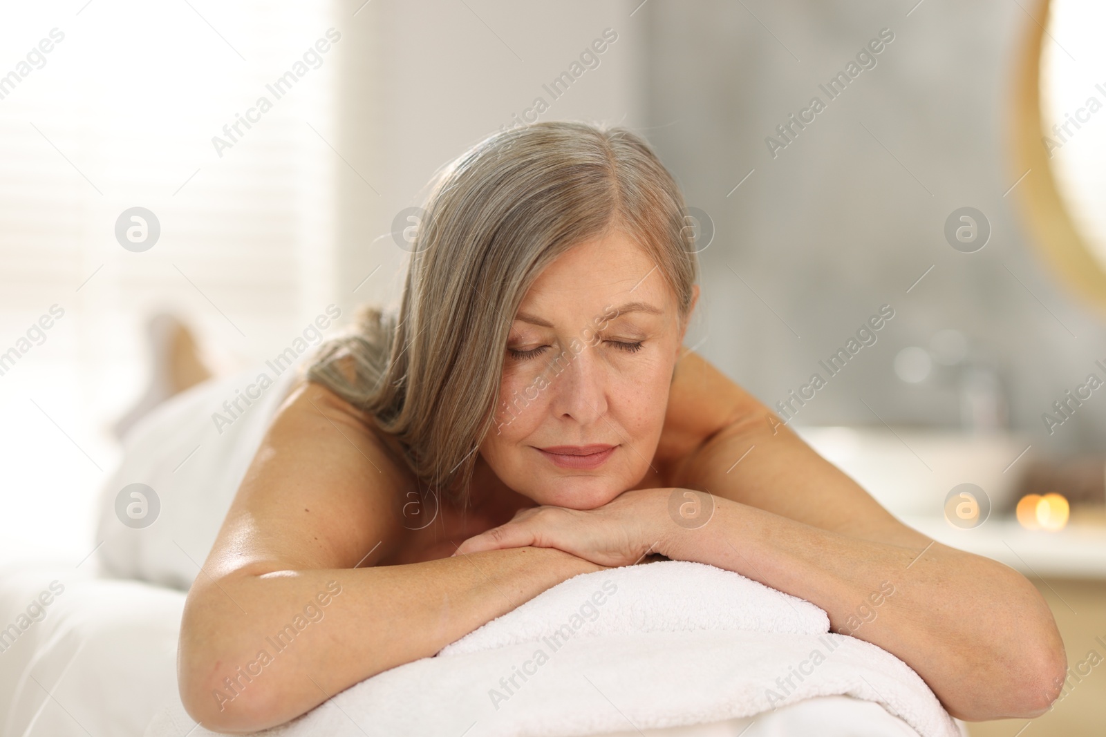 Senior woman relaxing on massage couch in spa salon Photo of Senior woman relaxing on massage couch in spa salon