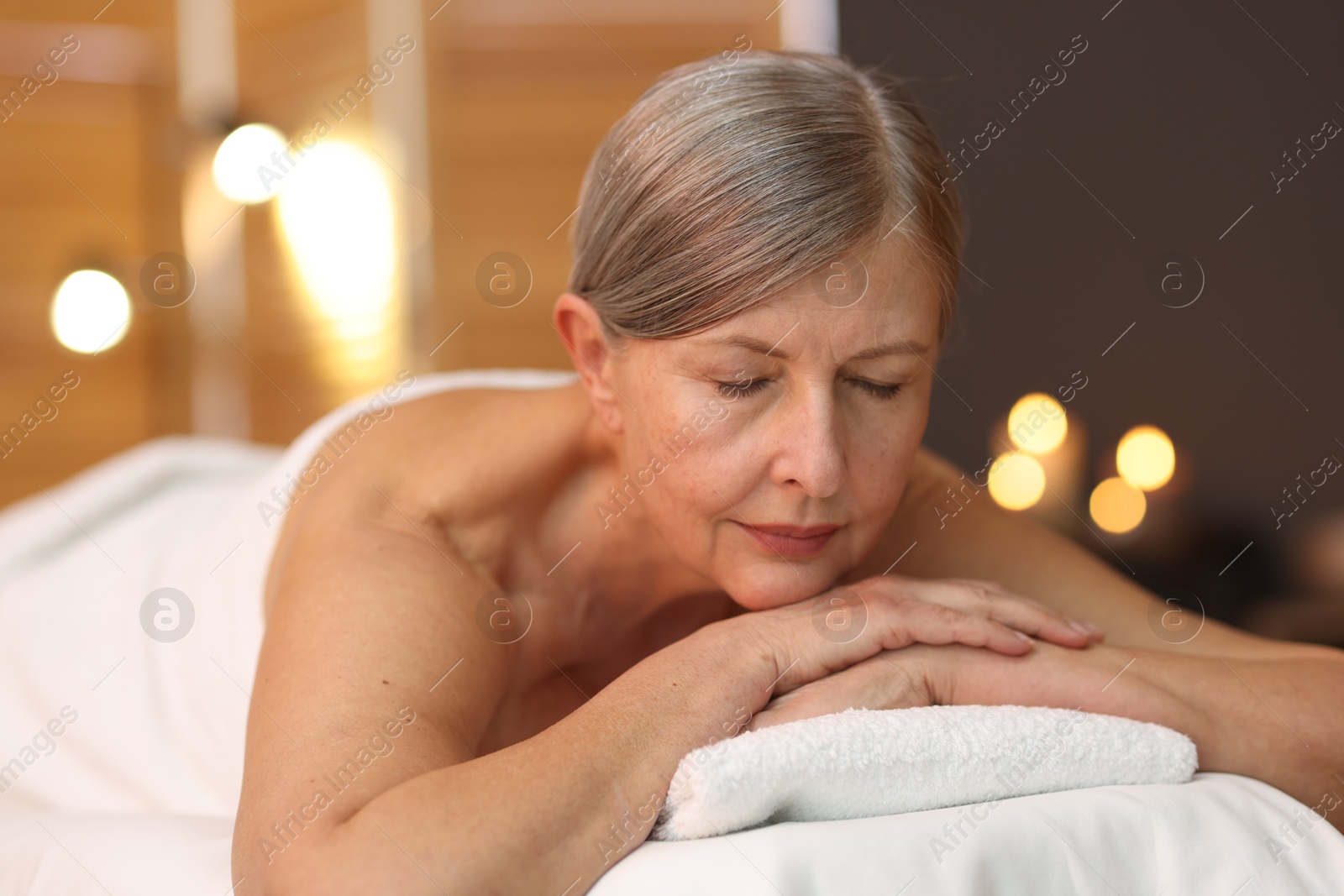 Senior woman relaxing on massage couch in spa salon Photo of Senior woman relaxing on massage couch in spa salon