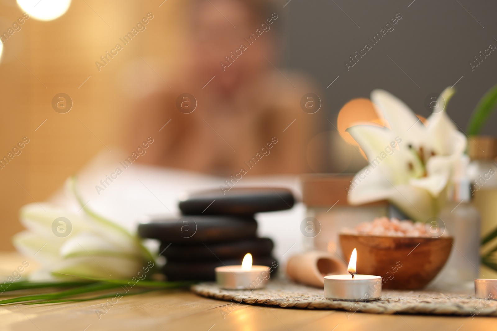 Beautiful woman relaxing on massage couch indoors, focus on different spa products and lily flowers Photo of Beautiful woman relaxing on massage couch indoors, focus on different spa products and lily flowers