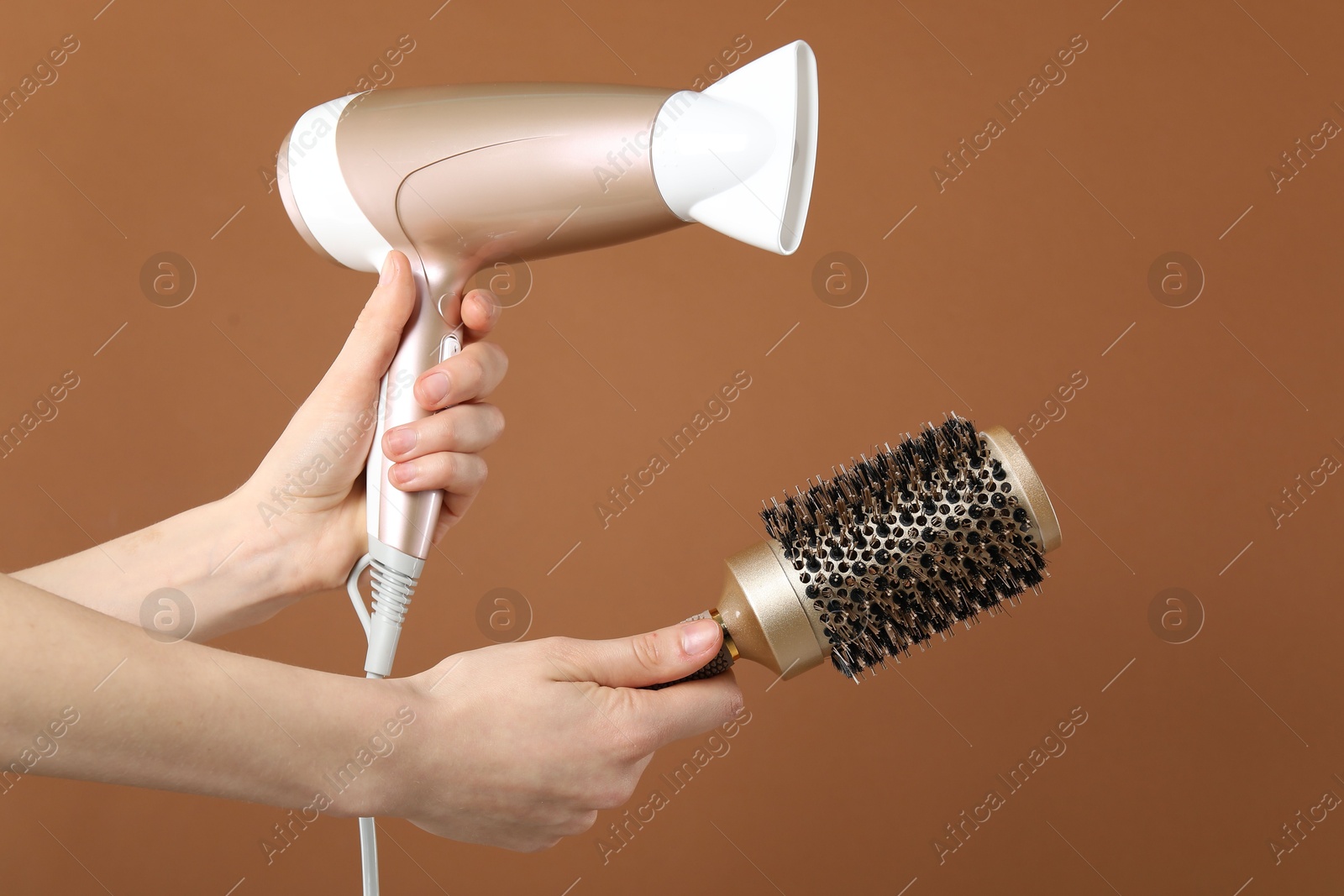 Woman with hair dryer and round brush on brown background, closeup Photo of Woman with hair dryer and round brush on brown background, closeup