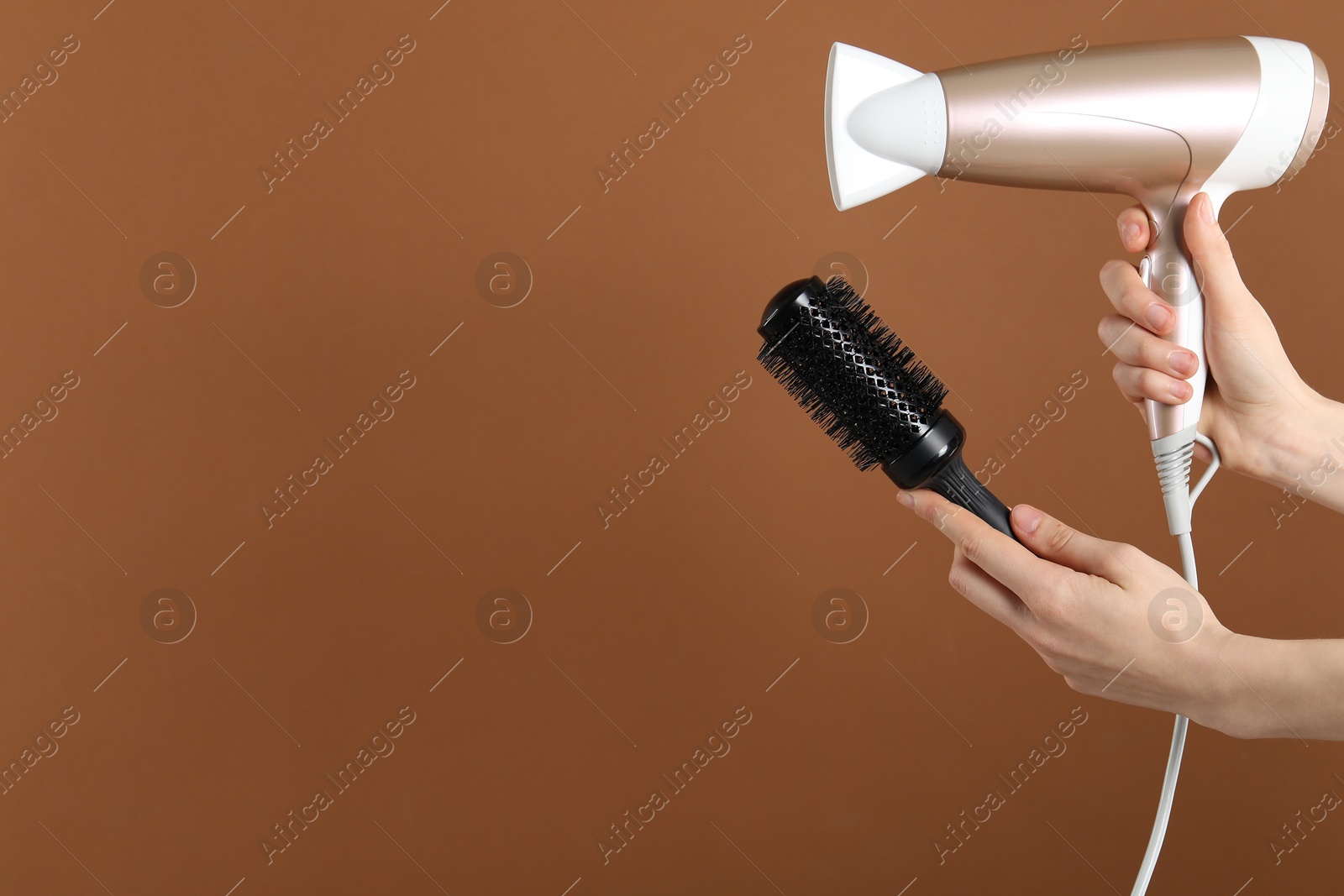 Woman with hair dryer and round brush on brown background, closeup. Space for text Photo of Woman with hair dryer and round brush on brown background, closeup. Space for text