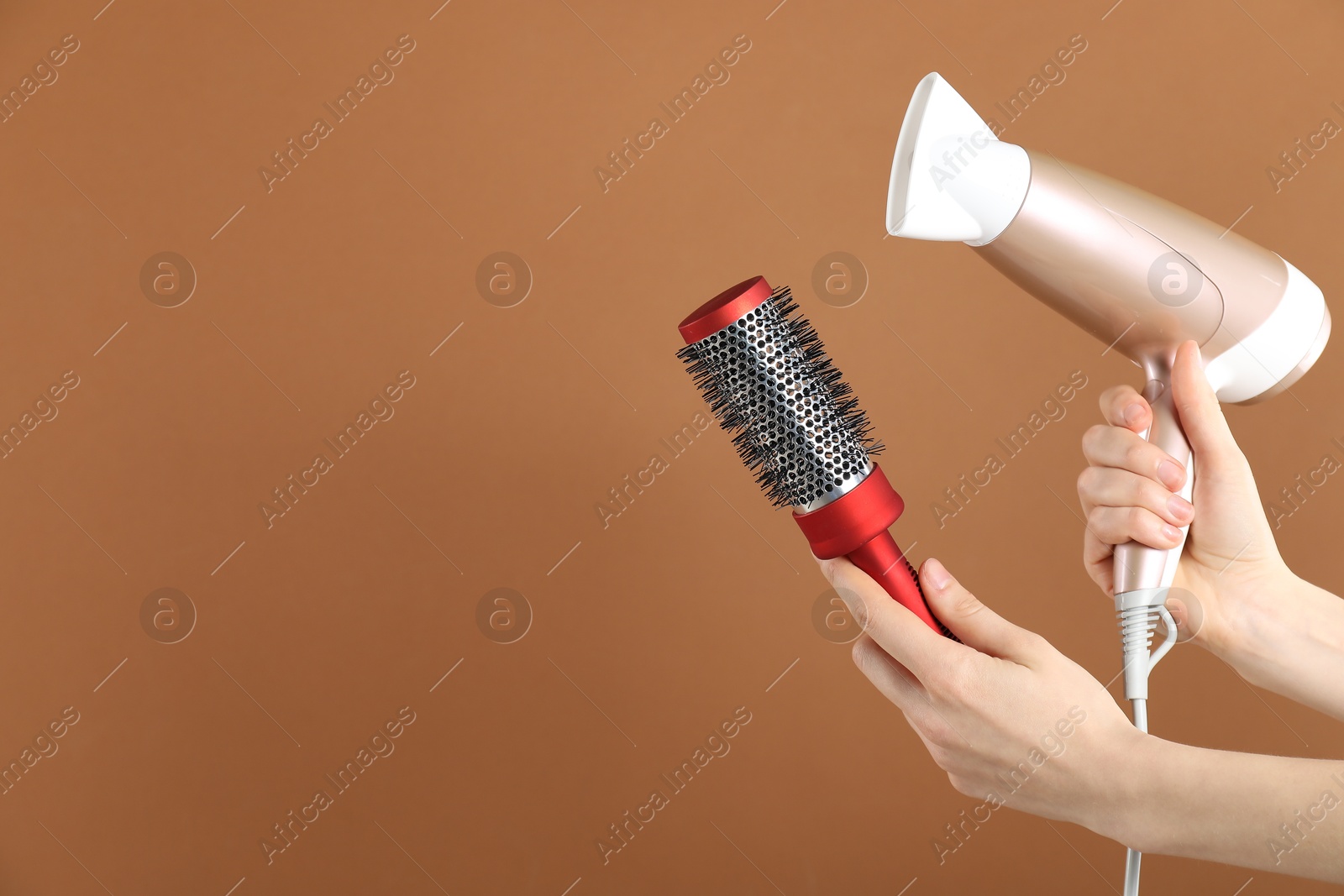 Woman with hair dryer and round brush on brown background, closeup. Space for text Photo of Woman with hair dryer and round brush on brown background, closeup. Space for text