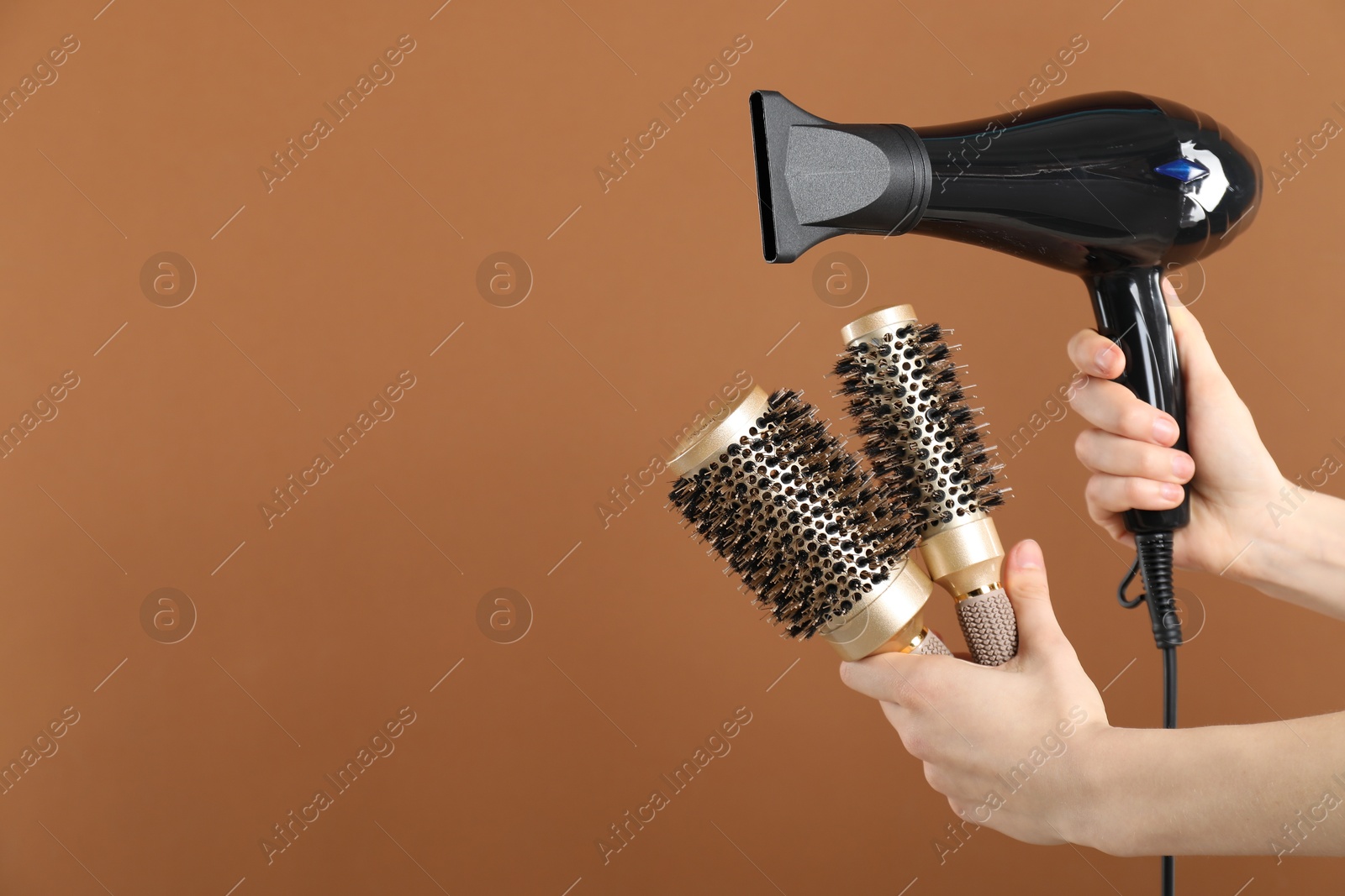 Woman with hair dryer and round brushes on brown background, closeup. Space for text Photo of Woman with hair dryer and round brushes on brown background, closeup. Space for text