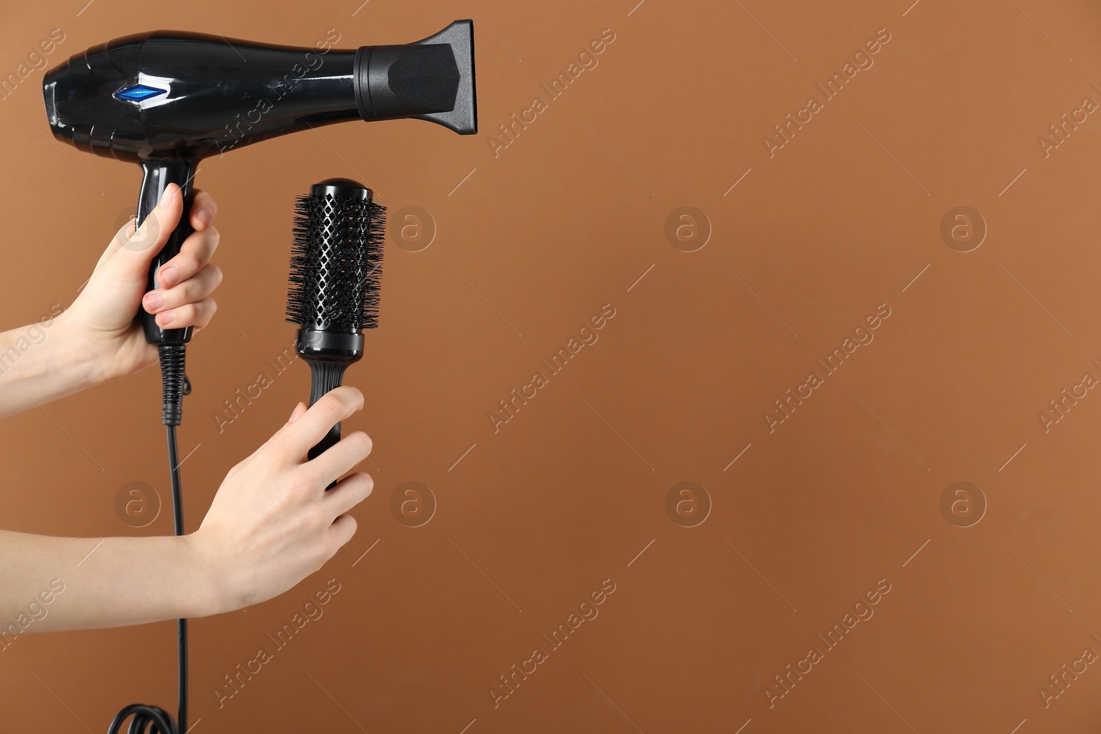Woman with hair dryer and round brush on brown background, closeup. Space for text Photo of Woman with hair dryer and round brush on brown background, closeup. Space for text