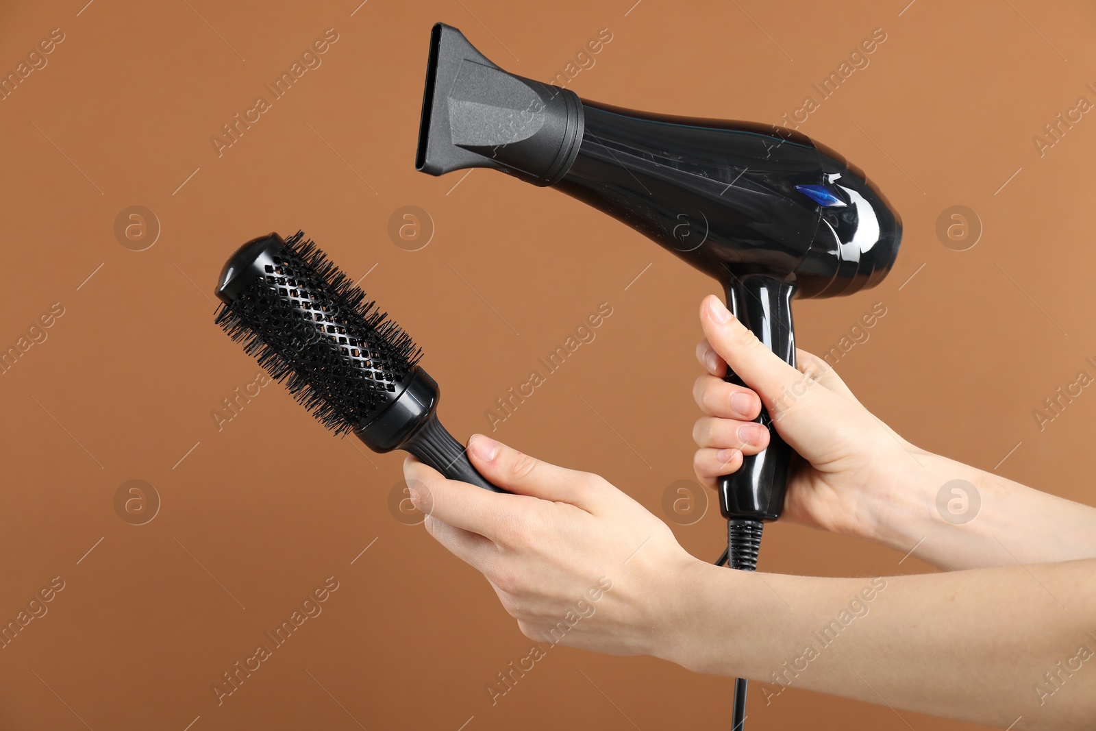Woman with hair dryer and round brush on brown background, closeup Photo of Woman with hair dryer and round brush on brown background, closeup
