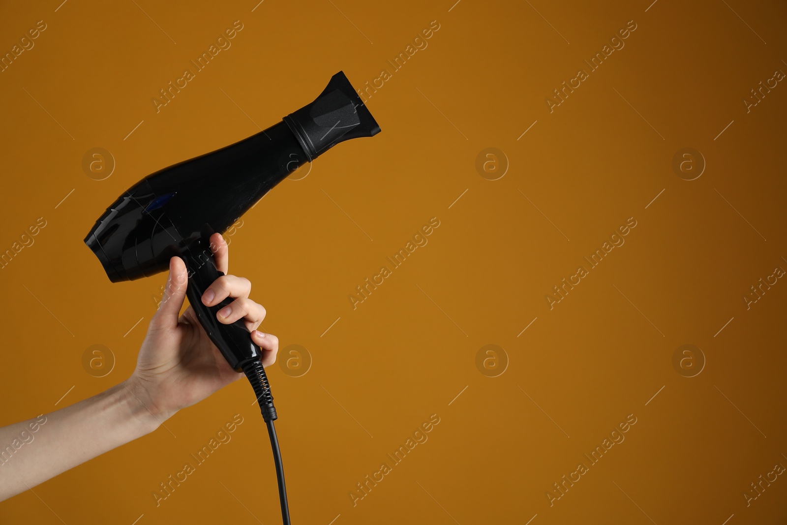 Woman with hair dryer on orange background, closeup. Space for text Photo of Woman with hair dryer on orange background, closeup. Space for text