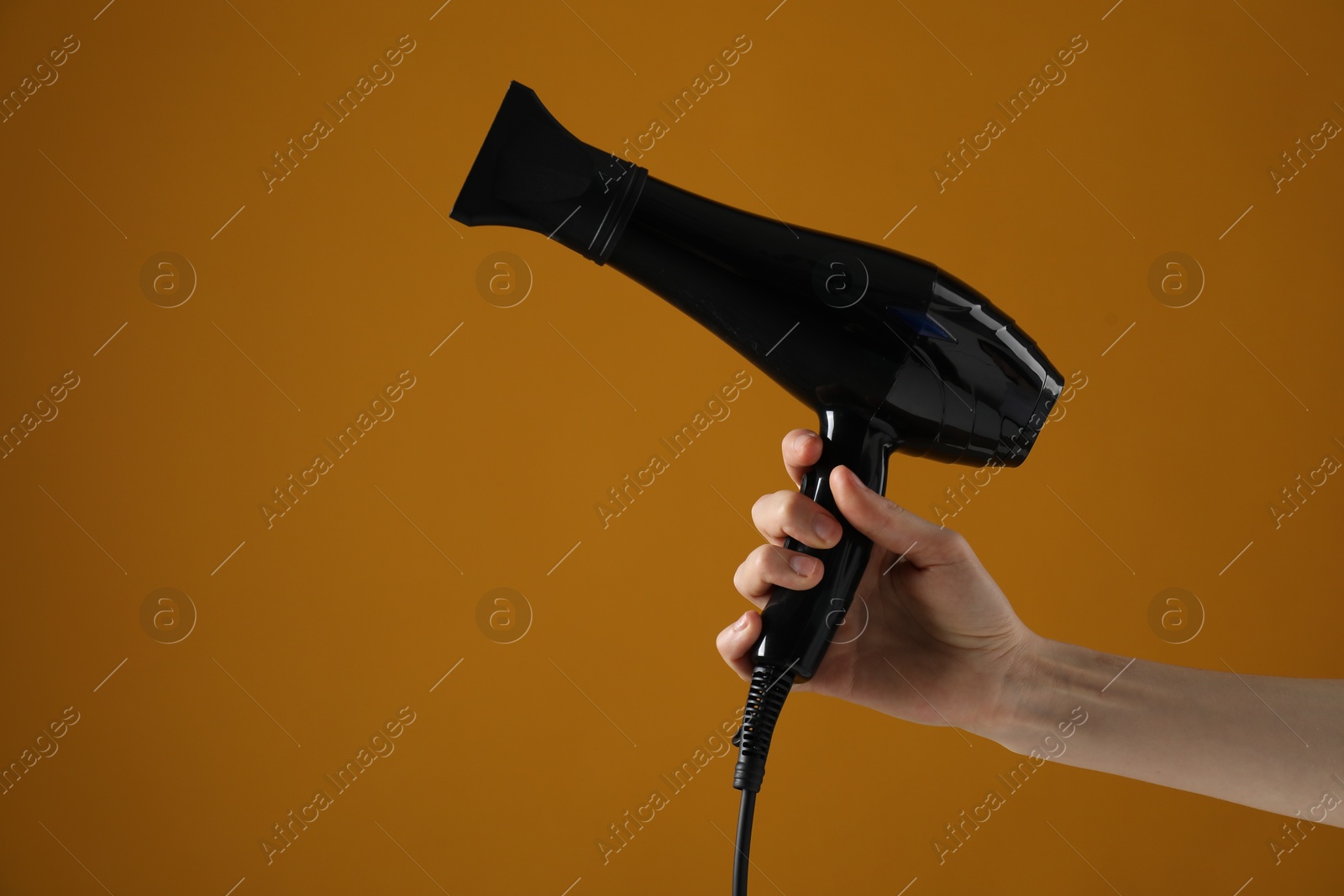 Woman with hair dryer on orange background, closeup. Space for text Photo of Woman with hair dryer on orange background, closeup. Space for text