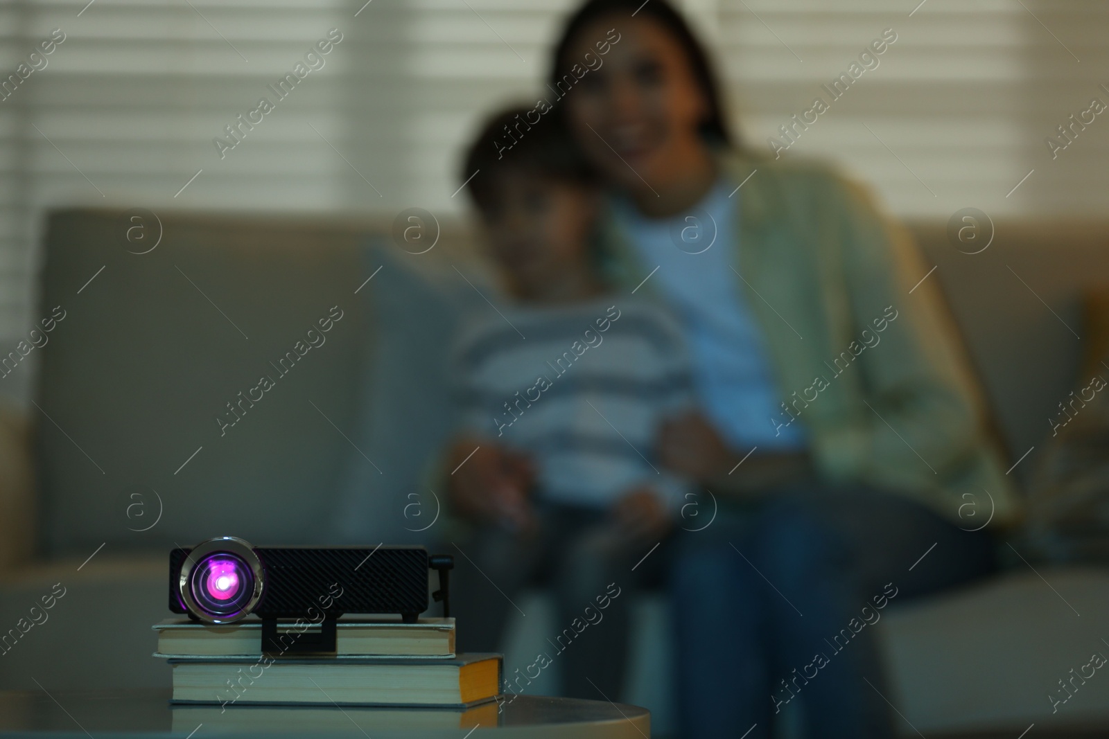 Young woman and her son watching movie at home, focus on video projector Photo of Young woman and her son watching movie at home, focus on video projector