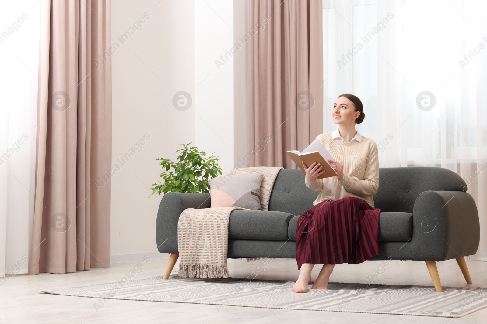 Woman reading book on sofa near window with stylish curtains at home. Space for text Photo of Woman reading book on sofa near window with stylish curtains at home. Space for text