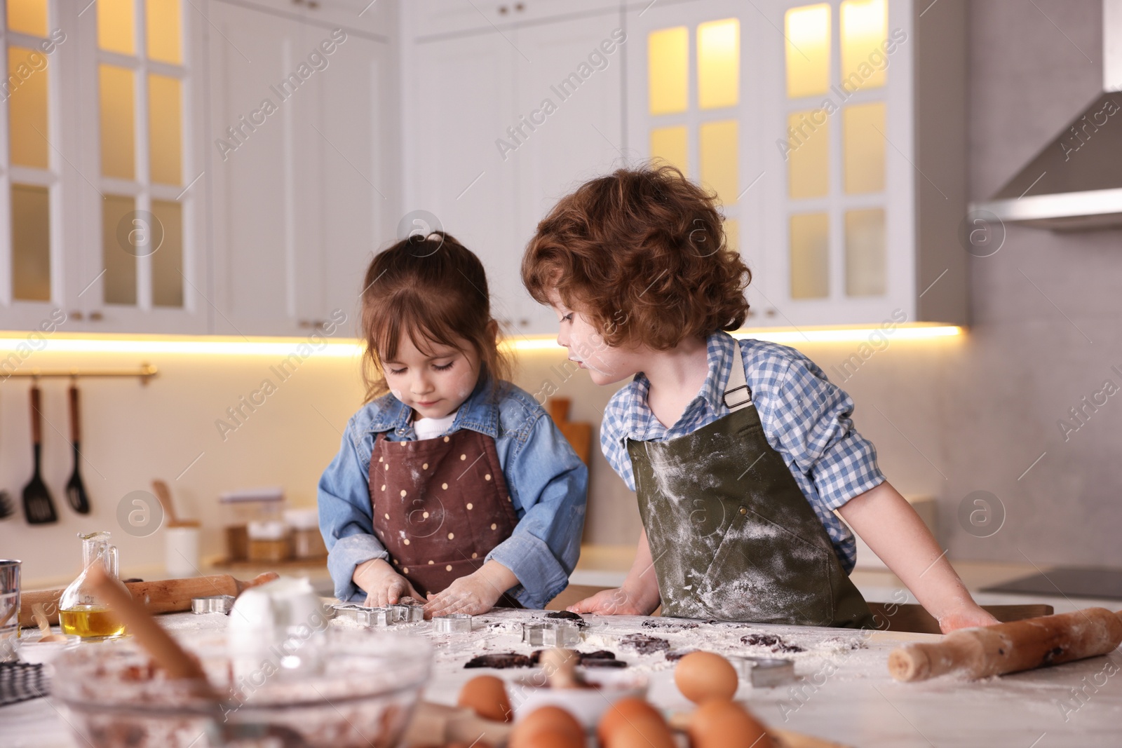Cooking recipe. Little children making dough for cookies at table in kitchen Photo of Cooking recipe. Little children making dough for cookies at table in kitchen