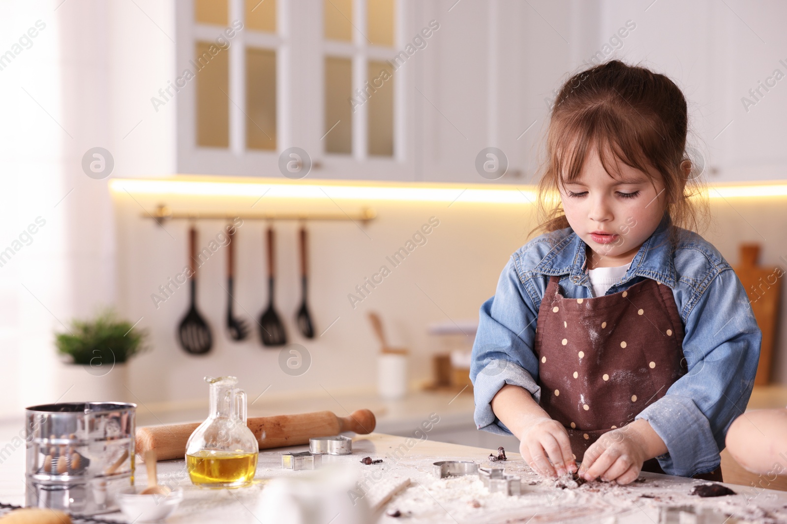 Cooking recipe. Little girl cutting cookies with cutters at table in kitchen. Space for text Photo of Cooking recipe. Little girl cutting cookies with cutters at table in kitchen. Space for text