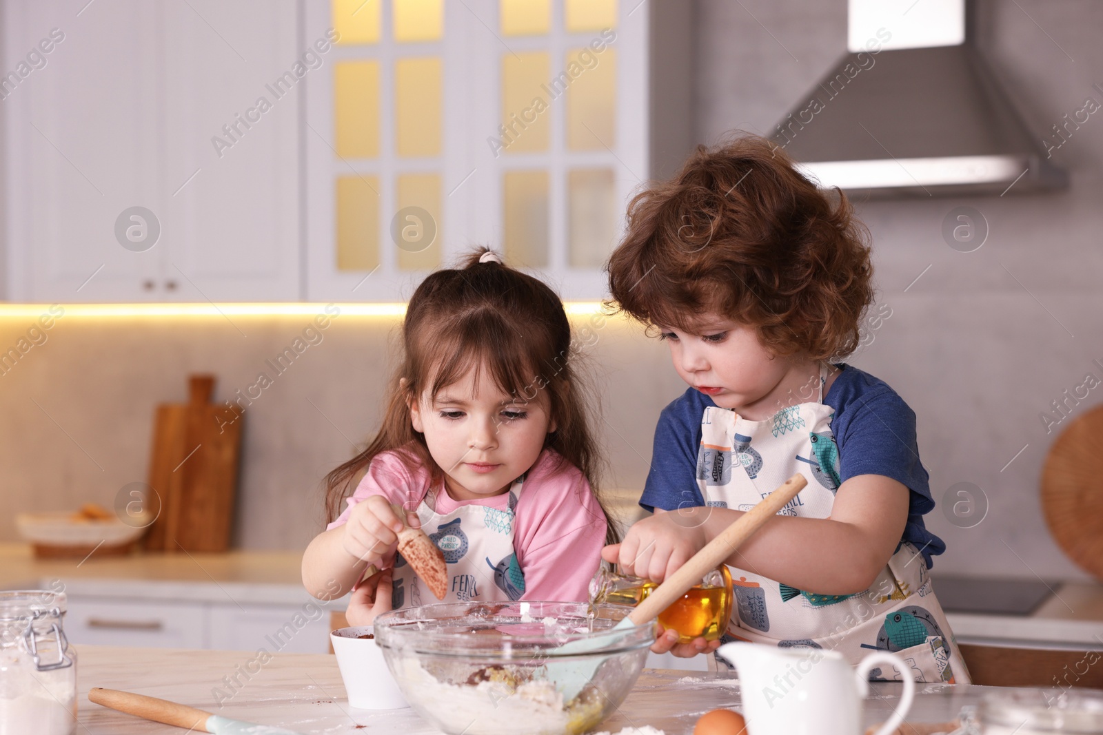 Cooking recipe. Cute children making dough for cookies at table in kitchen Photo of Cooking recipe. Cute children making dough for cookies at table in kitchen