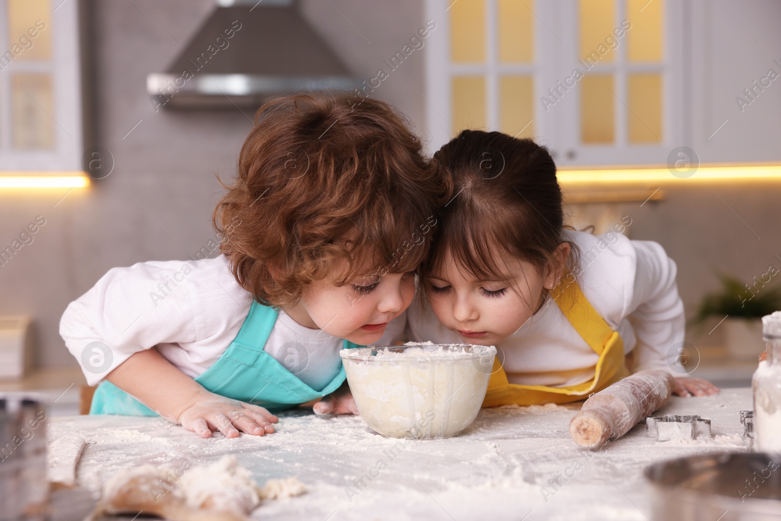 Cooking recipe. Little children smelling dough at table in kitchen Photo of Cooking recipe. Little children smelling dough at table in kitchen