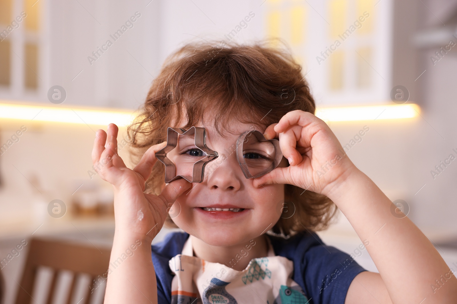 Cooking recipe. Cute boy with cookie cutters in kitchen Photo of Cooking recipe. Cute boy with cookie cutters in kitchen