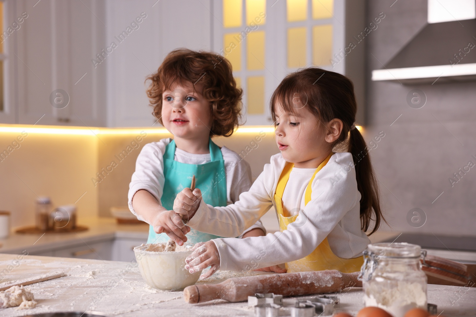 Cooking recipe. Cute children mixing dough for cookies at table in kitchen Photo of Cooking recipe. Cute children mixing dough for cookies at table in kitchen