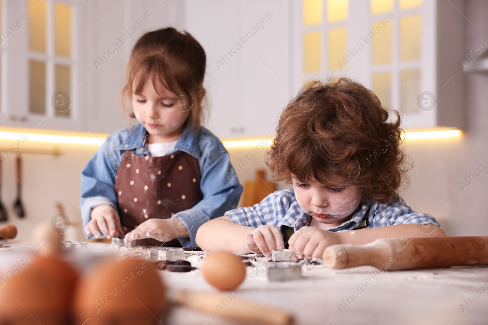 Cooking recipe. Little children cutting cookie dough with cutters at table indoors Photo of Cooking recipe. Little children cutting cookie dough with cutters at table indoors
