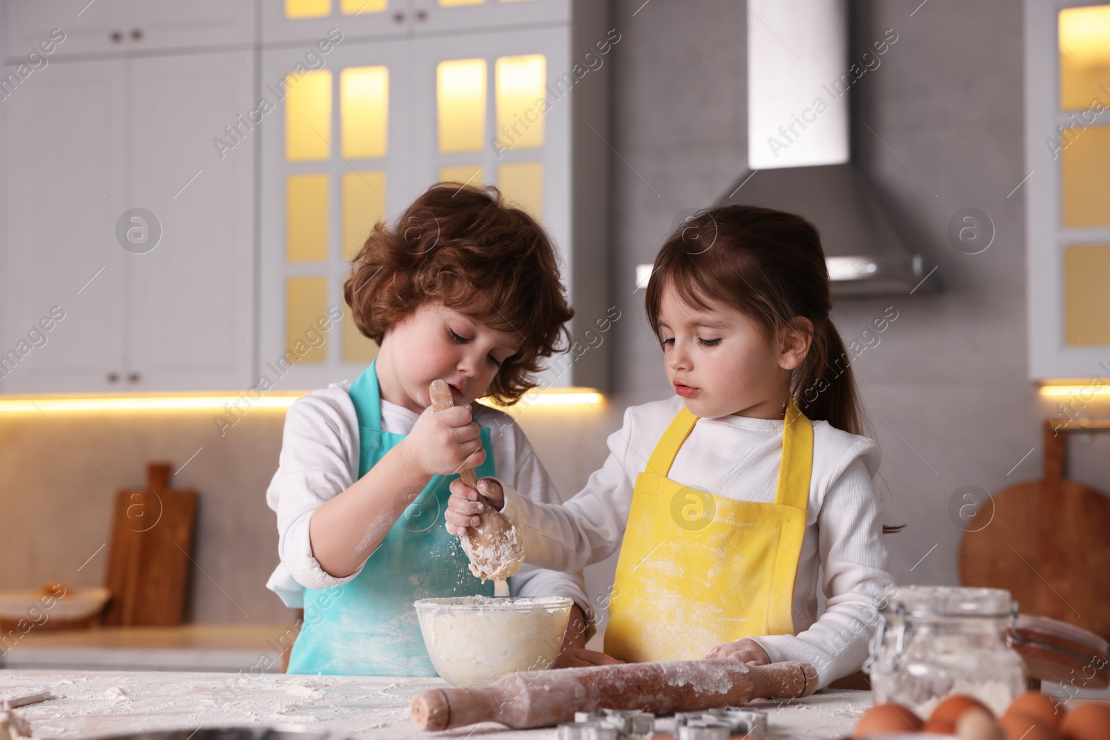 Cooking recipe. Cute children making dough for cookies at table in kitchen Photo of Cooking recipe. Cute children making dough for cookies at table in kitchen