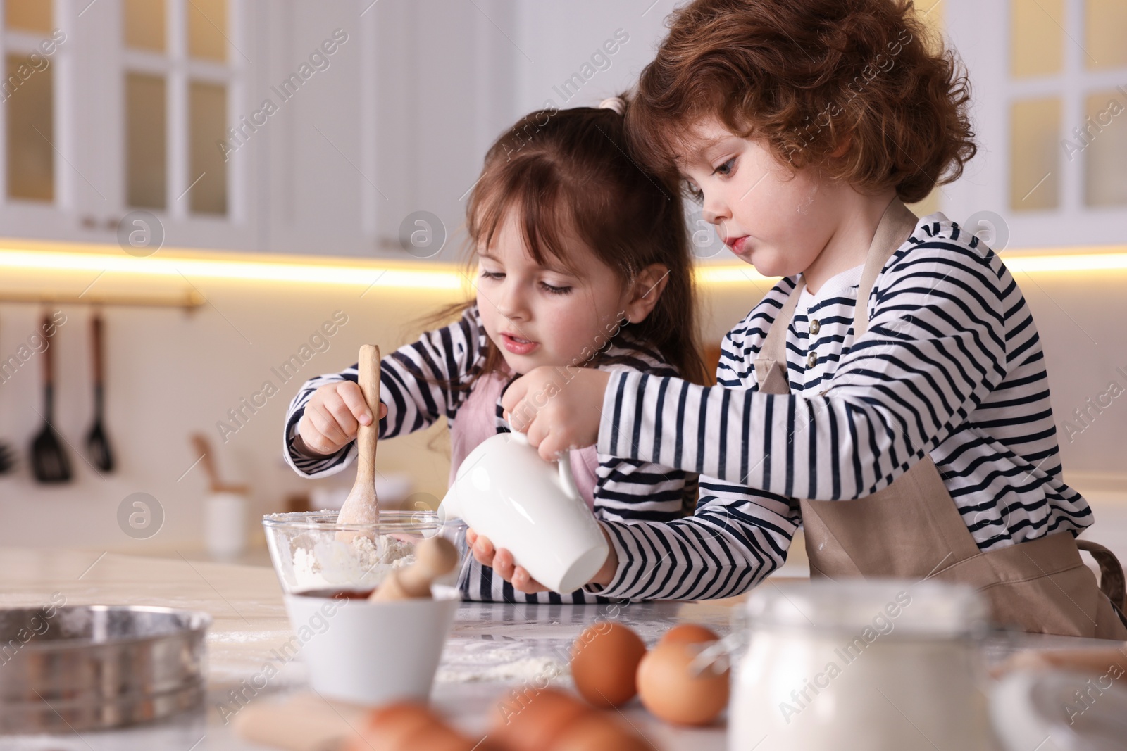 Cooking recipe. Cute children making dough for cookies at table in kitchen Photo of Cooking recipe. Cute children making dough for cookies at table in kitchen
