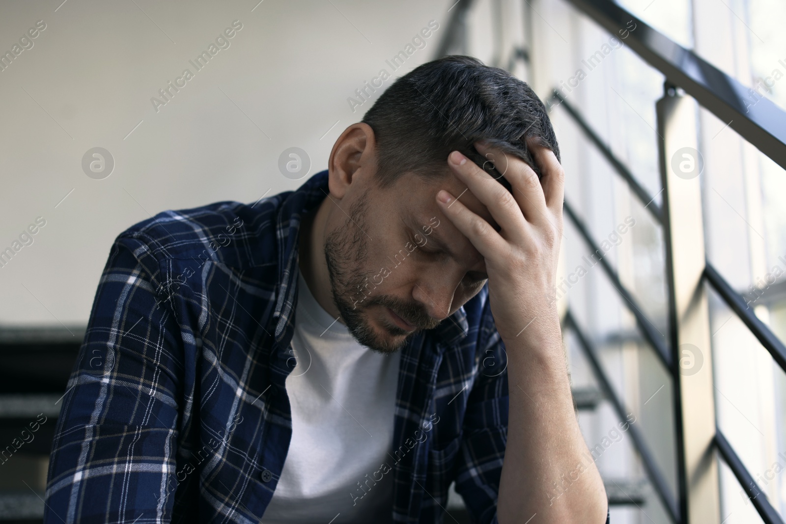 Depressed man sitting on stairs in building Photo of Depressed man sitting on stairs in building