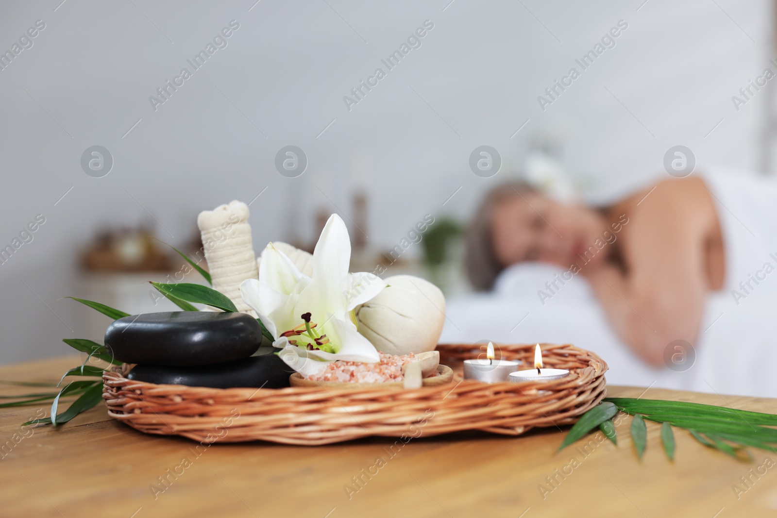 Senior woman relaxing on massage couch indoors, focus on different spa products and lily flower Photo of Senior woman relaxing on massage couch indoors, focus on different spa products and lily flower
