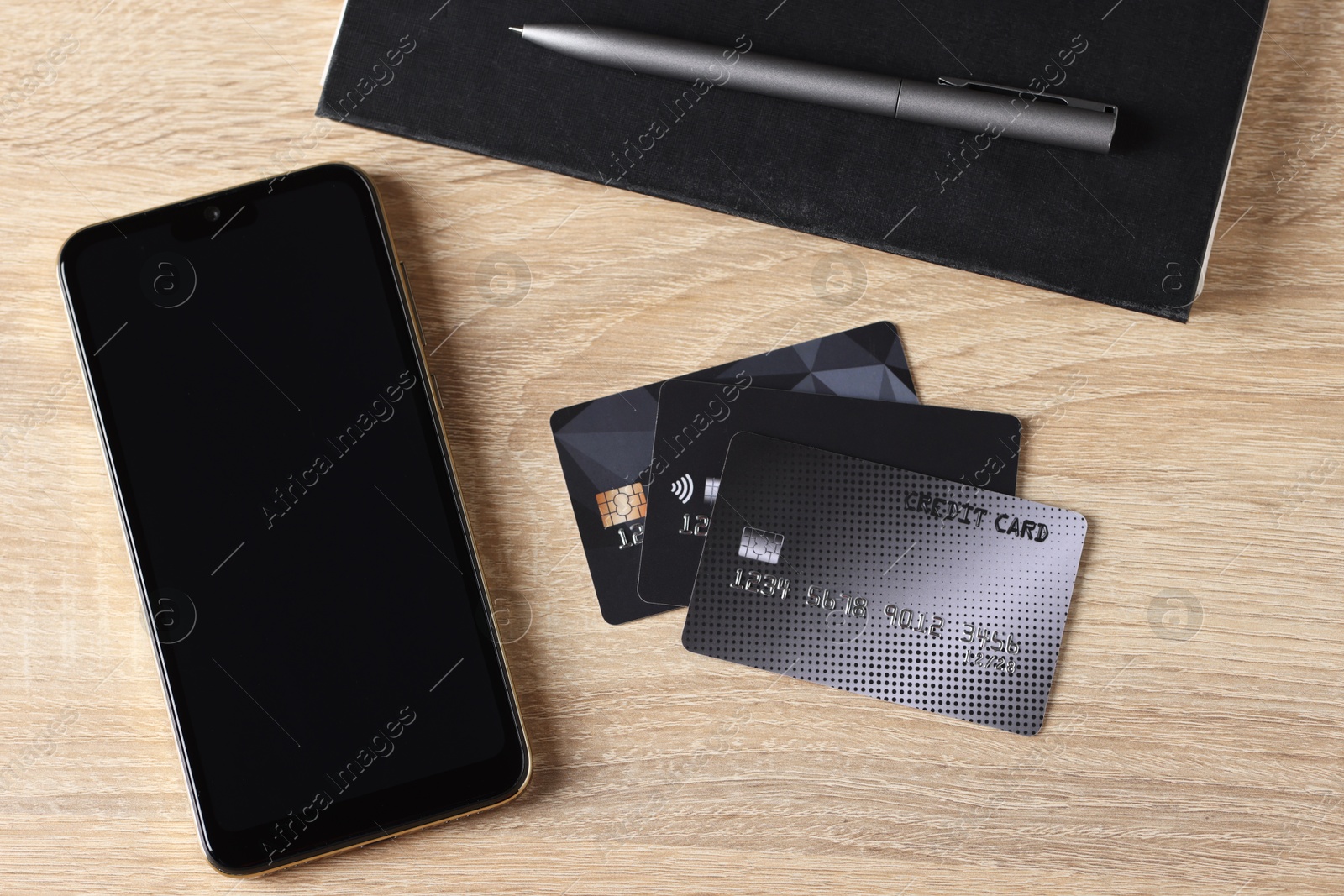 Photo of Online payment. Credit cards, smartphone and stationery on wooden table, flat lay