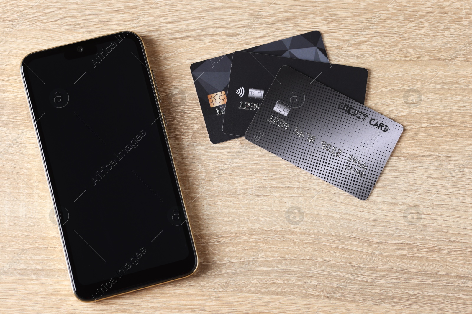 Photo of Online payment. Credit cards and smartphone on wooden table, flat lay