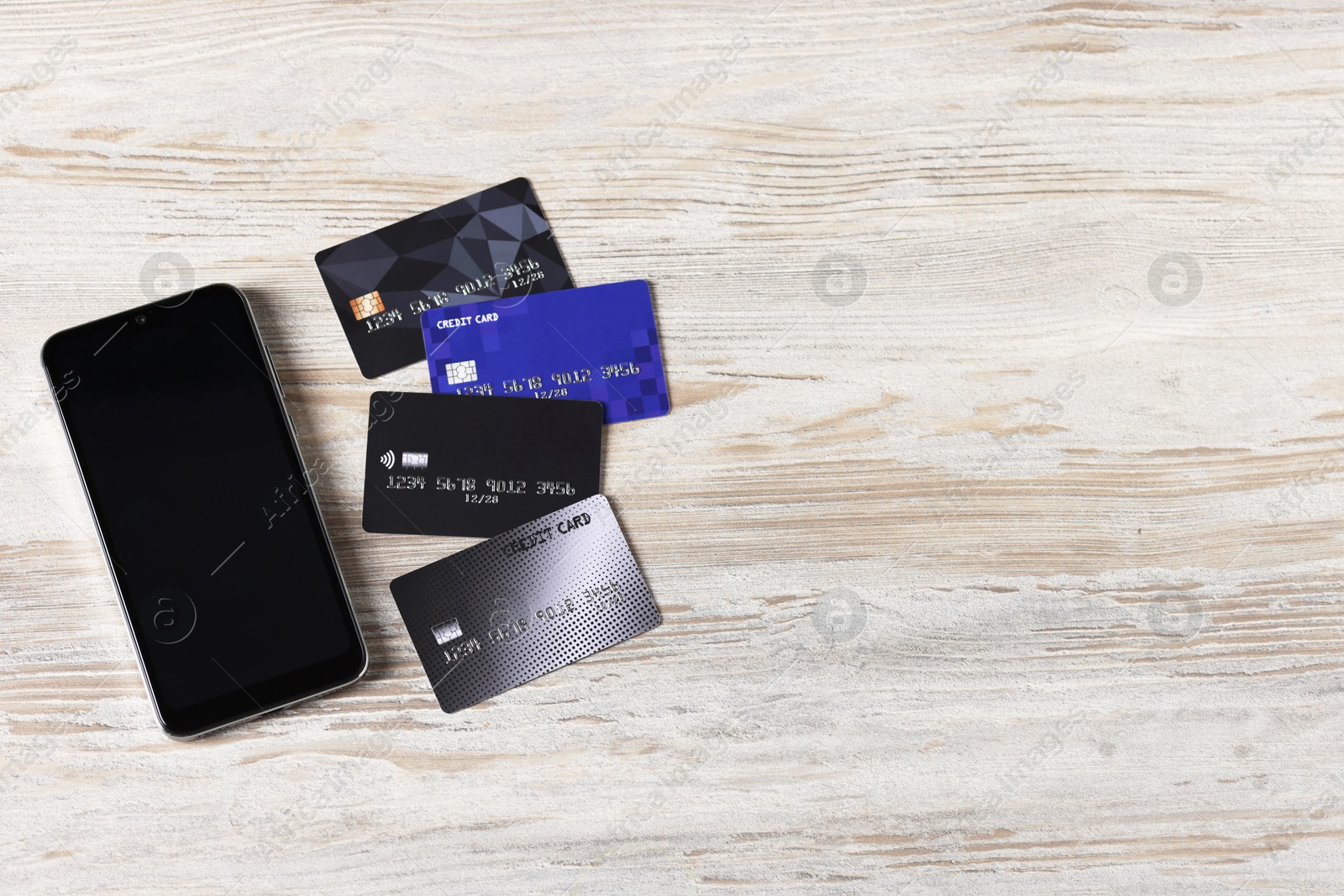 Photo of Online payment. Credit cards and smartphone on grey wooden table, flat lay. Space for text