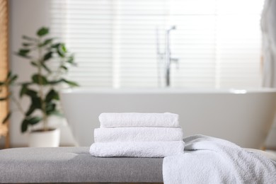 Photo of Stack of clean towels on bench in bathroom
