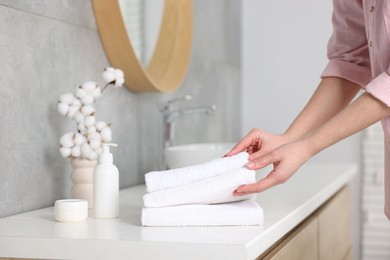 Photo of Woman taking clean towels from vanity in bathroom, closeup