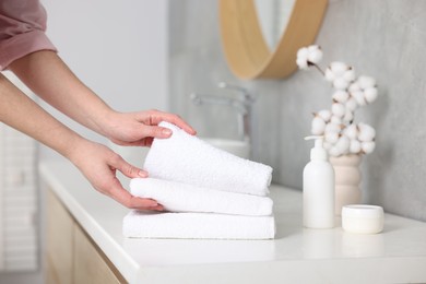 Photo of Woman taking clean towels from vanity in bathroom, closeup