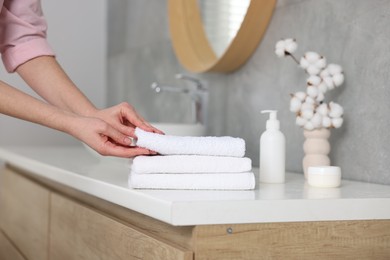 Photo of Woman taking clean towel from vanity in bathroom, closeup