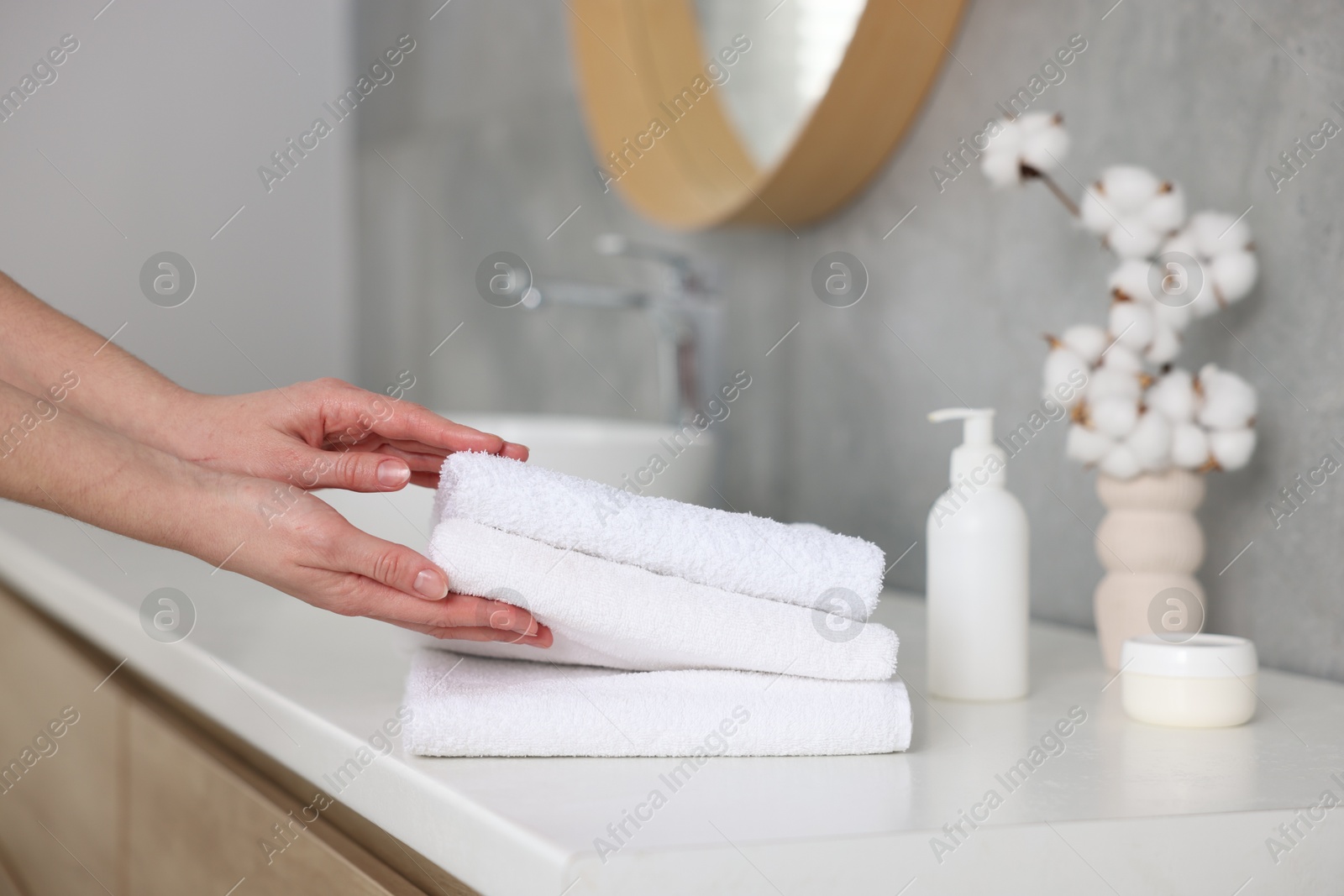 Woman taking clean towels from vanity in bathroom, closeup Photo of Woman taking clean towels from vanity in bathroom, closeup