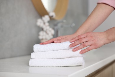 Photo of Woman taking clean towels from vanity in bathroom, closeup
