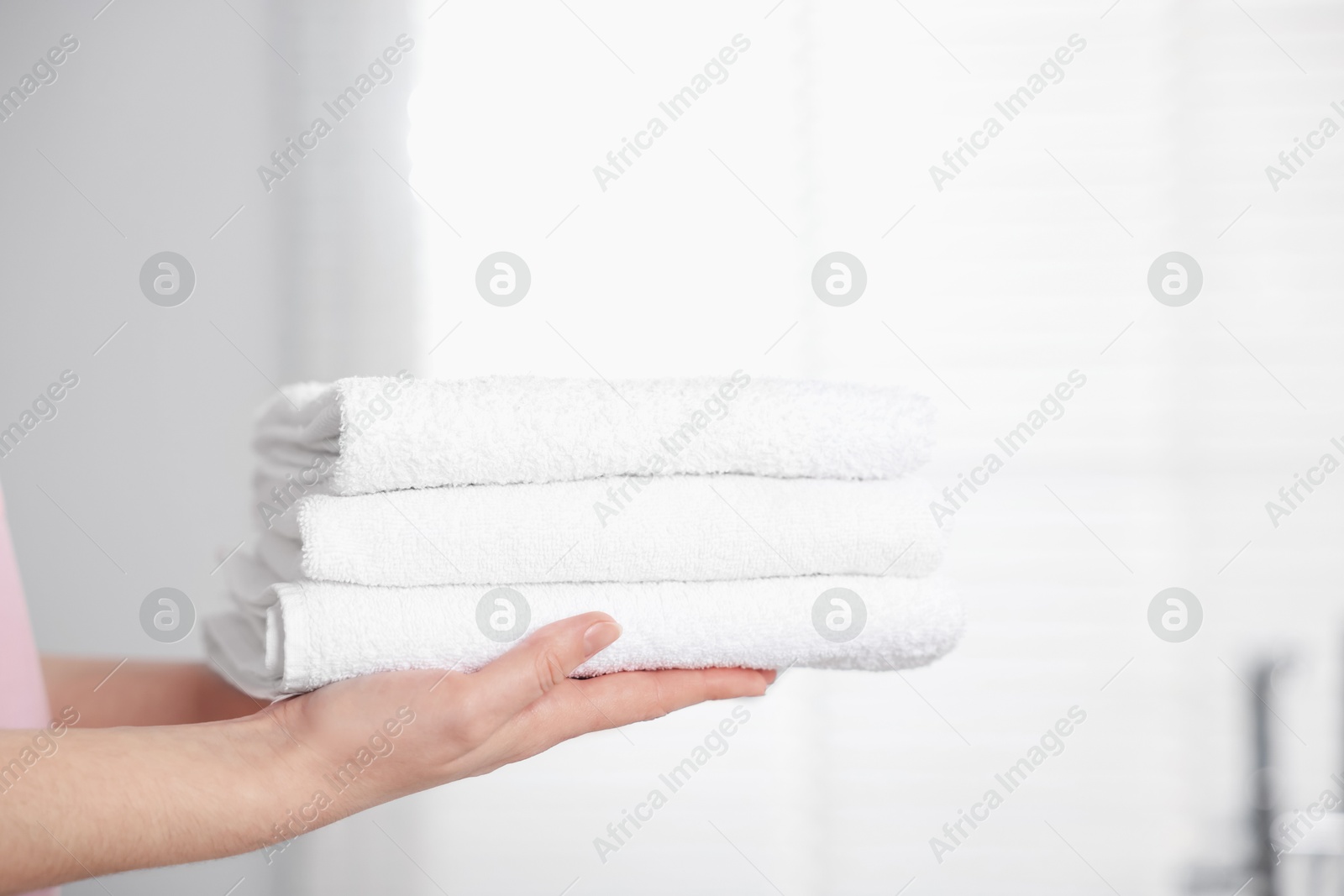 Woman with clean towels in bathroom, closeup Photo of Woman with clean towels in bathroom, closeup