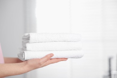 Photo of Woman with clean towels in bathroom, closeup