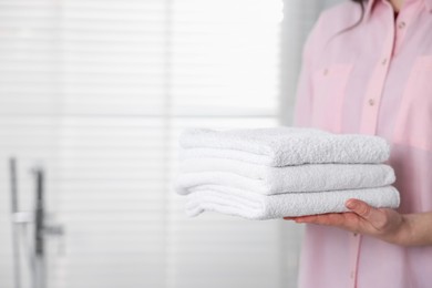 Photo of Woman with clean towels in bathroom, closeup. Space for text