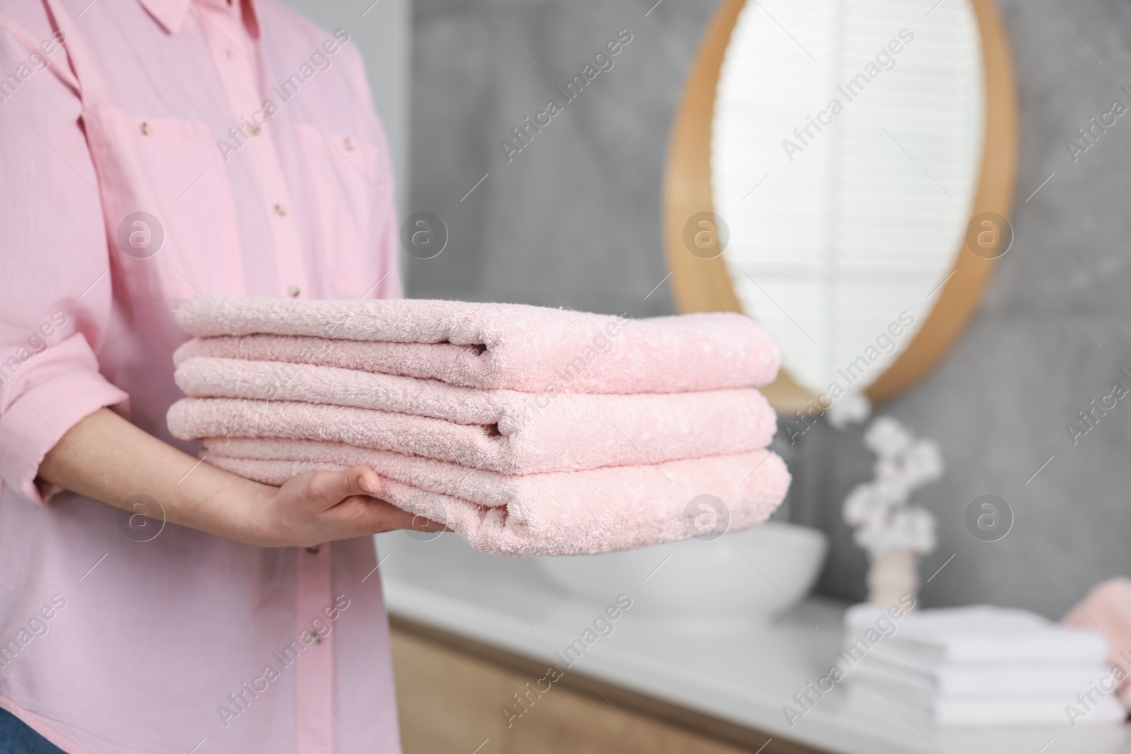 Woman with clean towels in bathroom, closeup Photo of Woman with clean towels in bathroom, closeup
