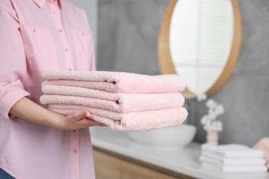 Photo of Woman with clean towels in bathroom, closeup