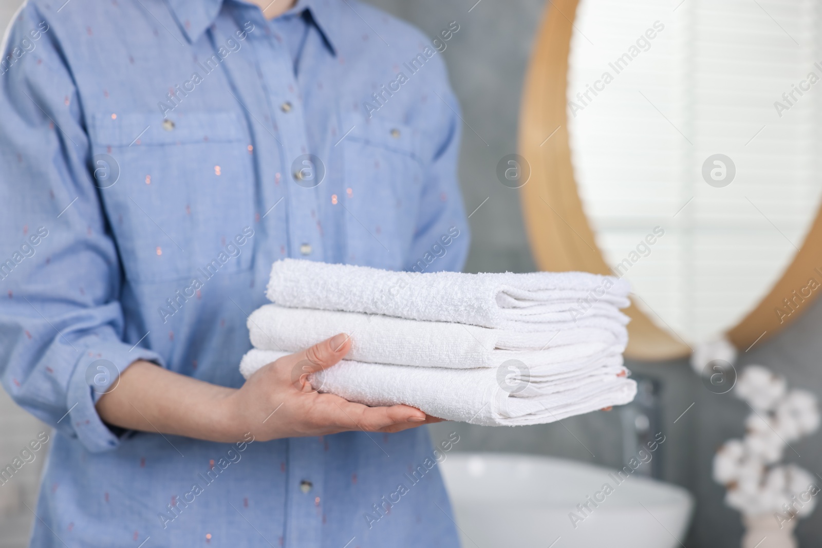 Woman with clean towels in bathroom, closeup Photo of Woman with clean towels in bathroom, closeup