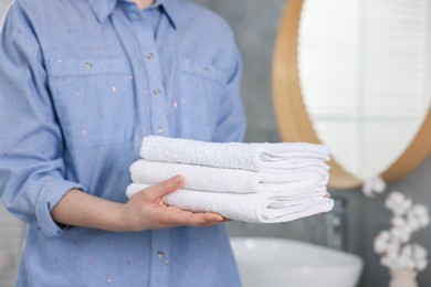 Photo of Woman with clean towels in bathroom, closeup