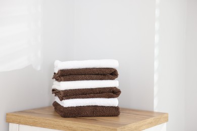 Photo of Stack of clean towels on wooden cabinet indoors