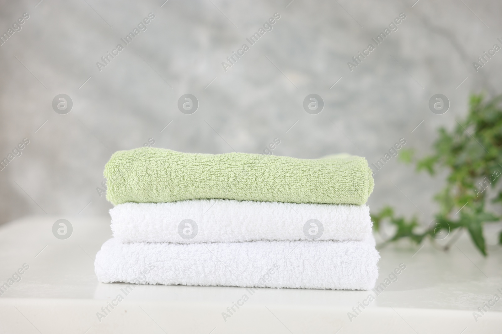 Stack of clean towels on white table indoors, closeup Photo of Stack of clean towels on white table indoors, closeup