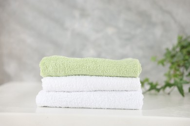 Photo of Stack of clean towels on white table indoors, closeup