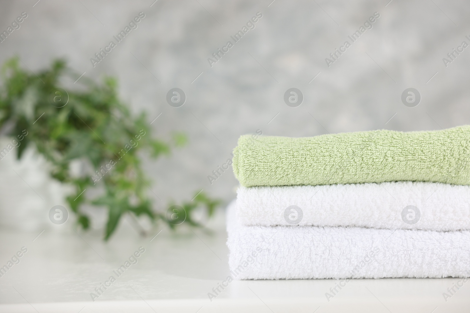 Stack of clean towels on white table indoors, closeup. Space for text Photo of Stack of clean towels on white table indoors, closeup. Space for text