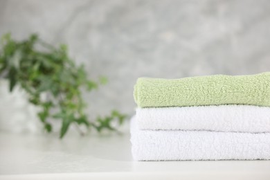 Photo of Stack of clean towels on white table indoors, closeup. Space for text