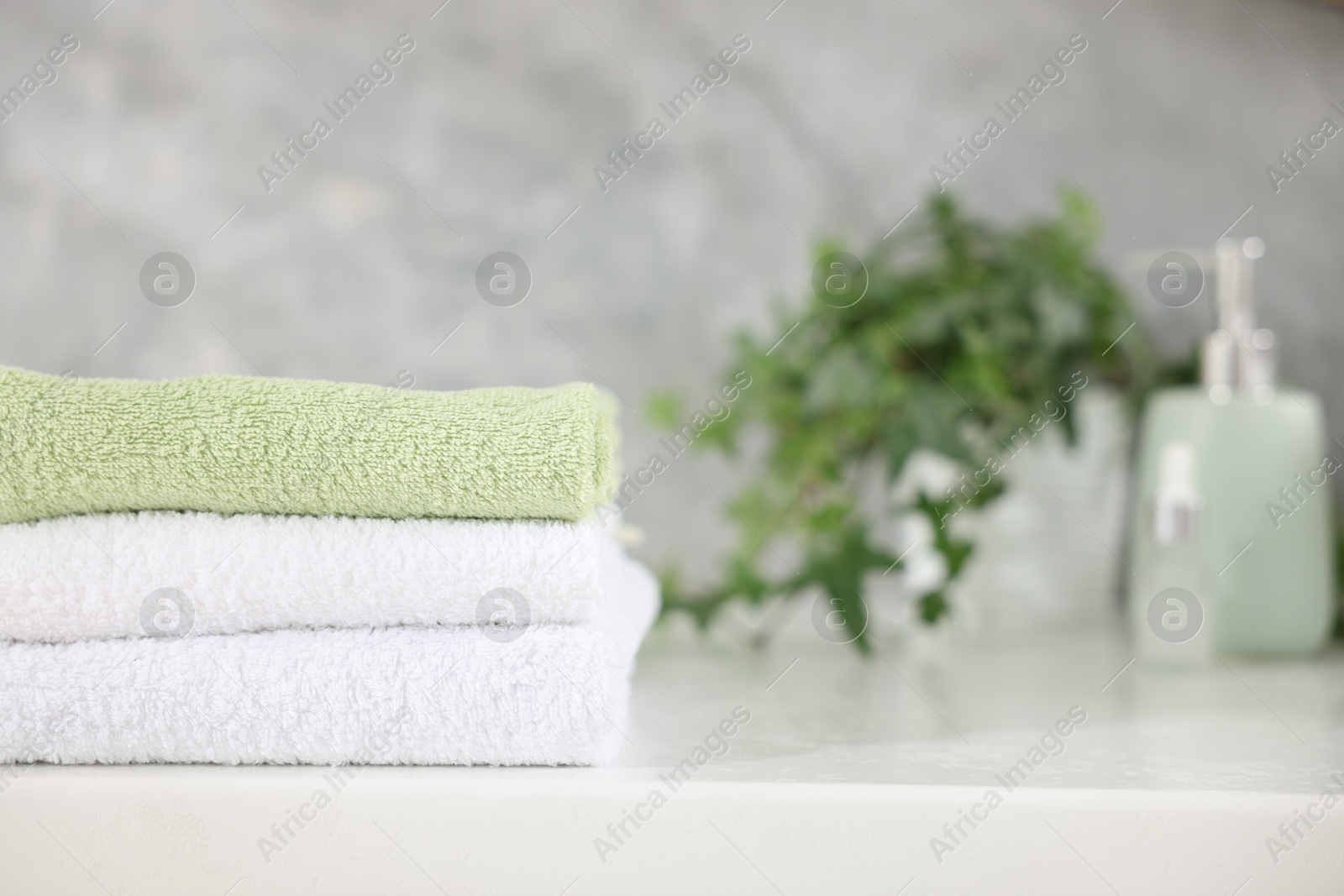 Stack of clean towels on white table indoors, closeup. Space for text Photo of Stack of clean towels on white table indoors, closeup. Space for text
