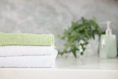 Photo of Stack of clean towels on white table indoors, closeup. Space for text