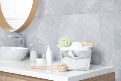 Photo of Clean towels in basket, cosmetic products and brush on vanity indoors