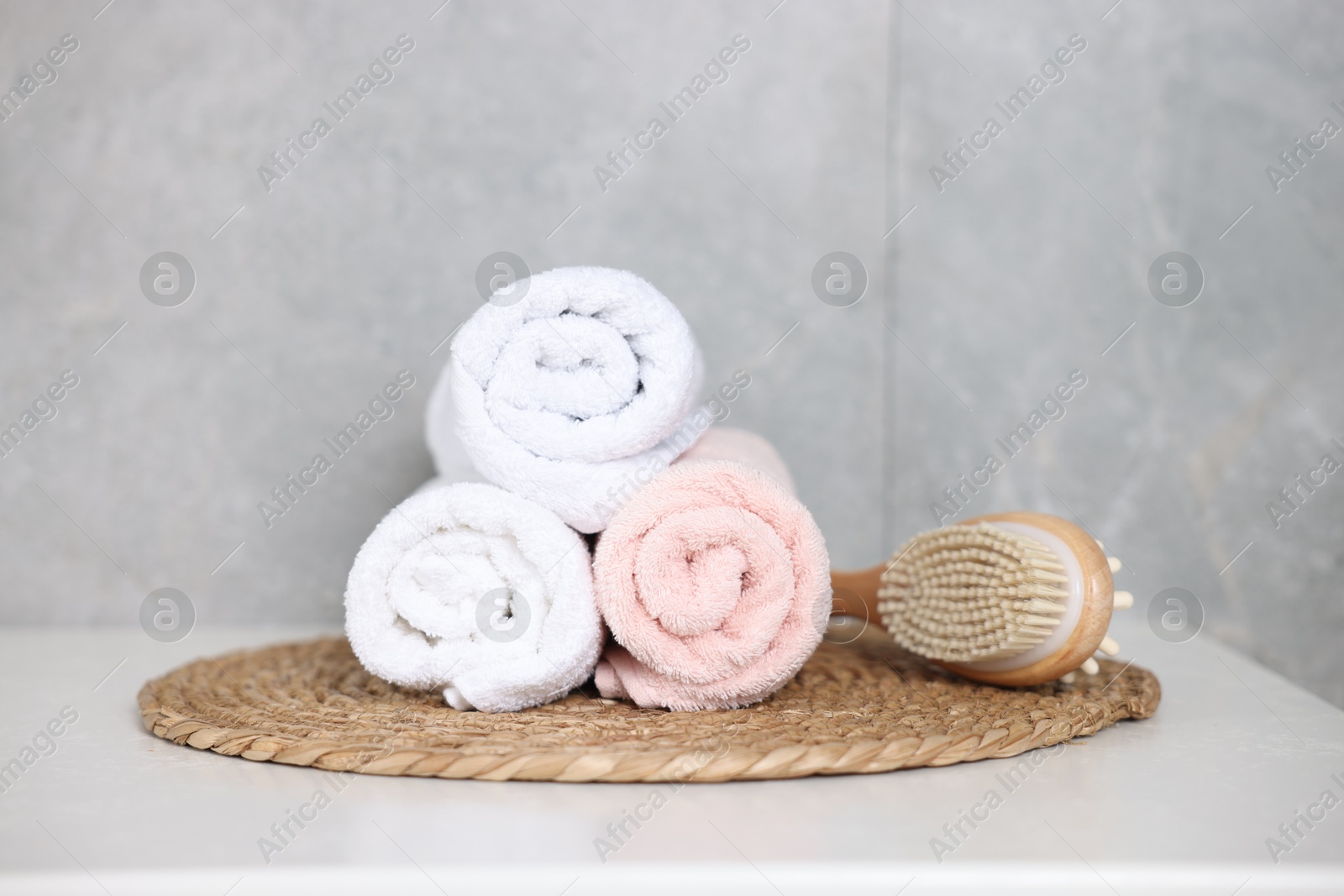 Clean towels and brush on white table indoors Photo of Clean towels and brush on white table indoors