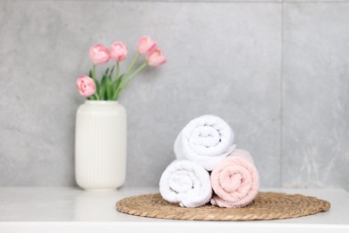 Photo of Clean towels and beautiful flowers on white table indoors